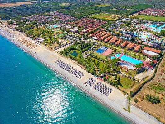 Vista aerea di un resort costiero con spiaggia e piscine.