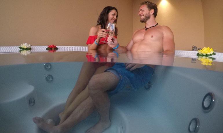 Coppia felice brinda in jacuzzi, atmosfera romantica e rilassante.