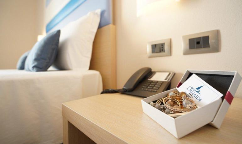 Camera accogliente con letto, telefono e scatola di gioielli sul comodino.