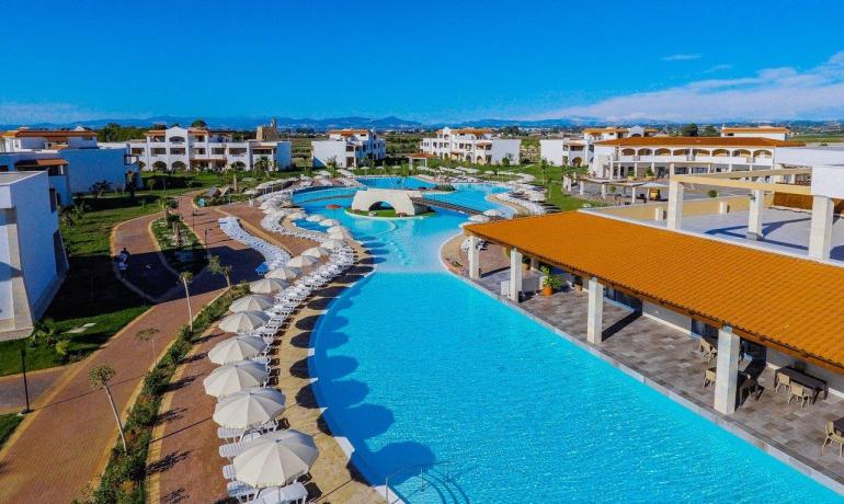 Un resort con piscina scintillante, ombrelloni e cielo azzurro.