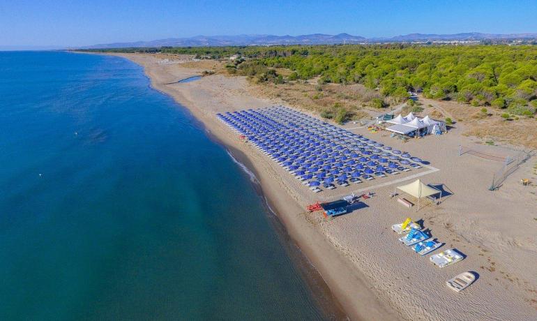 Spiaggia infinita, mare blu, ombrelloni ordinati, quiete e serenità.