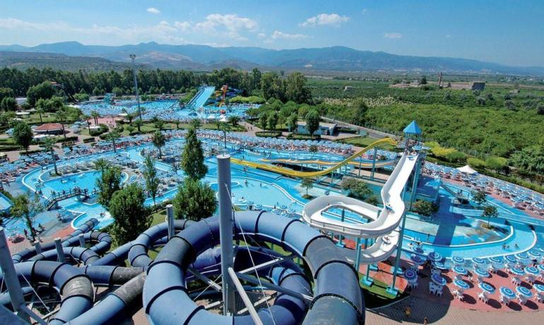 Parco acquatico vibrante con scivoli emozionanti e piscine rinfrescanti, circondato da natura.