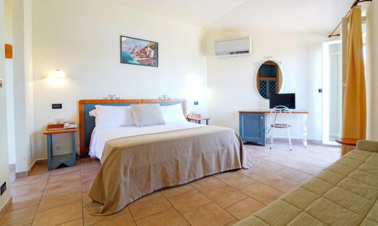Camera accogliente, letto matrimoniale, arredi eleganti, atmosfera rilassante, luce calda.