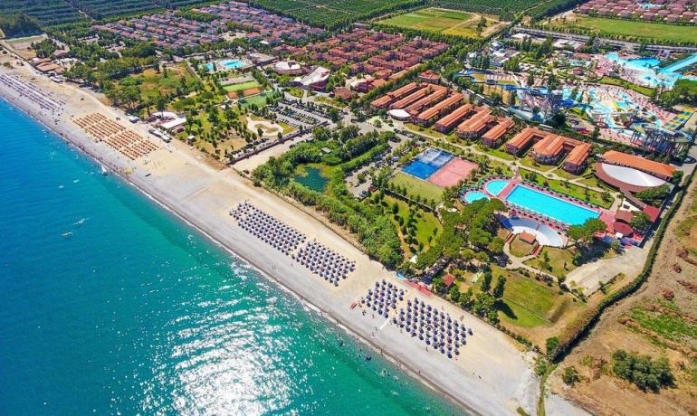Vista aerea di un resort costiero con spiaggia e piscine.