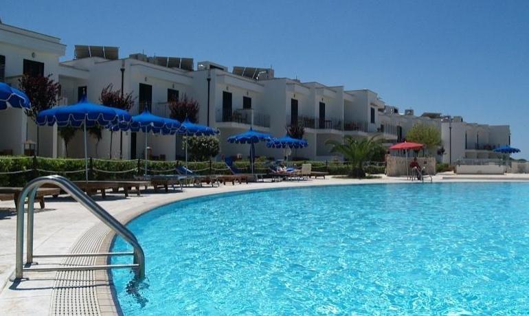 Piscina azzurra, ombrelloni blu, cielo sereno, relax estivo.