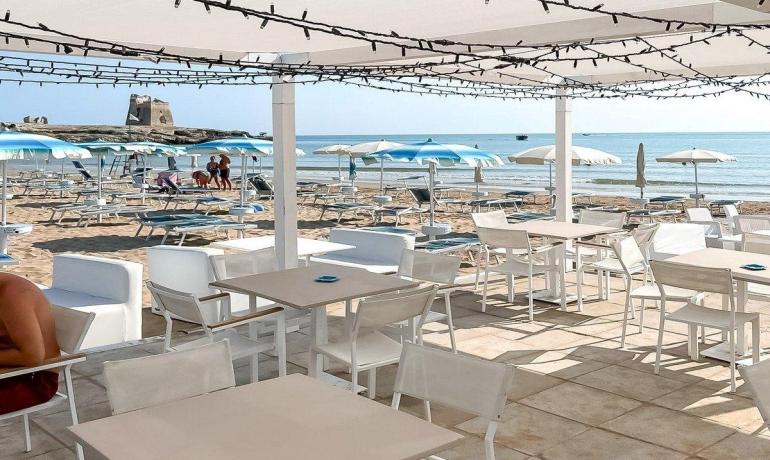 Spiaggia soleggiata, ombrelloni azzurri, mare calmo e relax totale.