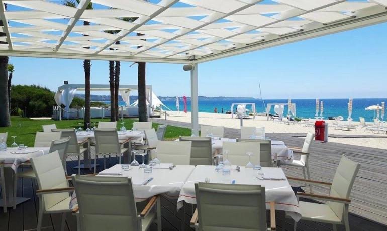 Ristorante elegante sulla spiaggia, mare azzurro e cielo limpido.