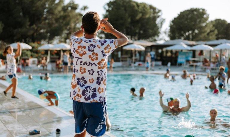 Animatore guida giochi in piscina, atmosfera estiva e gioiosa.