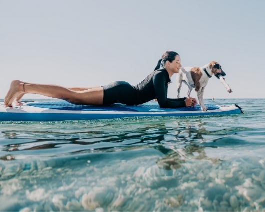 Donna e cane su paddleboard, rilassati sull'acqua cristallina.