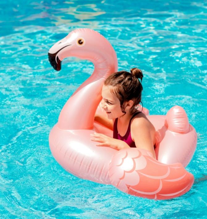 Bambina su un gonfiabile a forma di fenicottero in piscina.